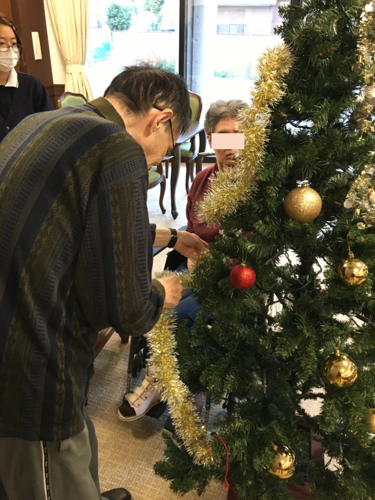 男性がクリスマスツリーの飾り付けをしている